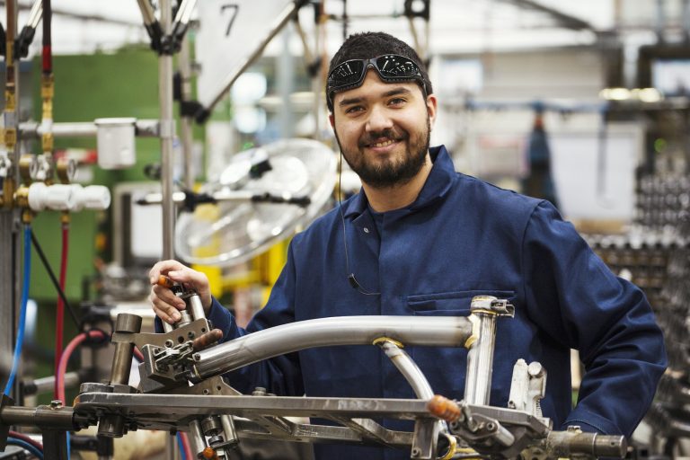Male skilled factory worker with a partly assembled bicycle frame in a factory.
