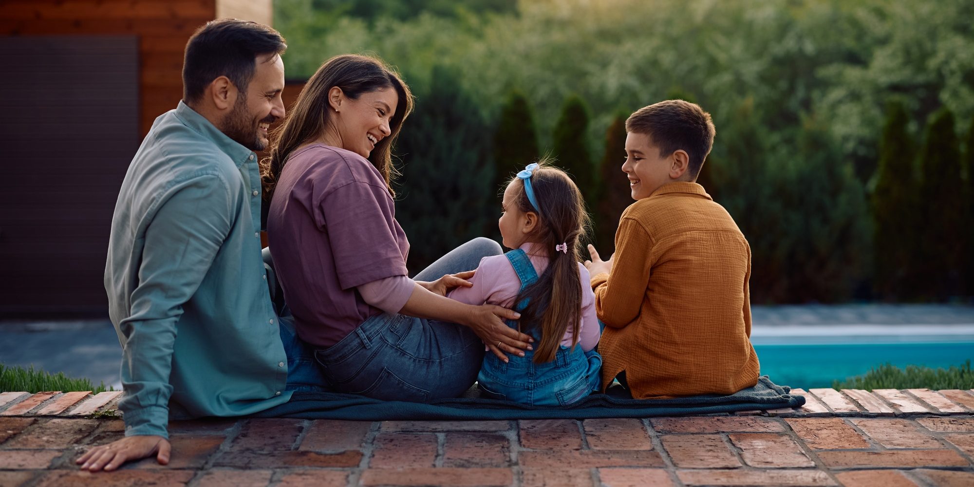 Happy family relaxing by the pool in their backyard.